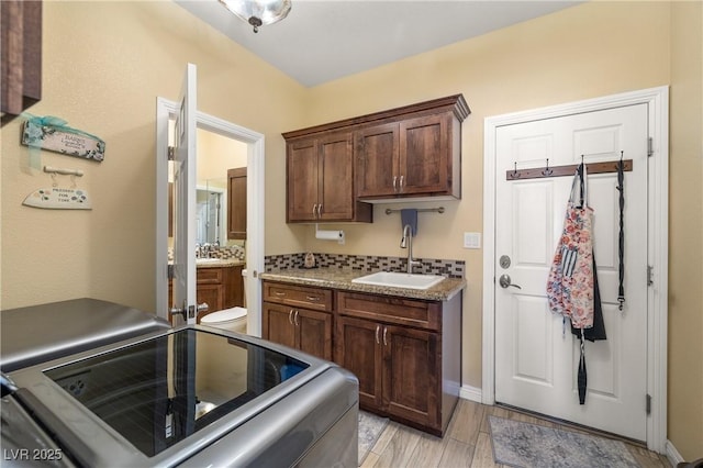 kitchen featuring decorative backsplash, stove, dark brown cabinets, and sink