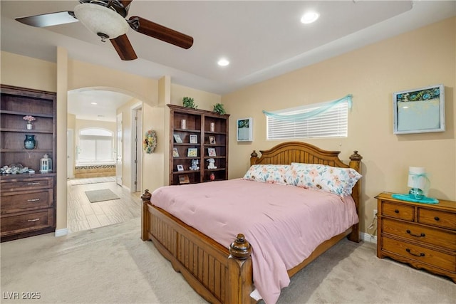 bedroom featuring ceiling fan, light carpet, and ensuite bath