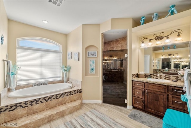 bathroom with hardwood / wood-style floors, vanity, and plus walk in shower