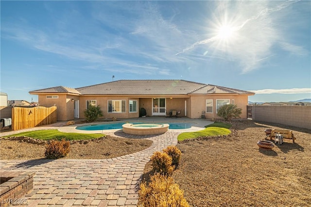 rear view of house featuring a swimming pool with hot tub and a patio area