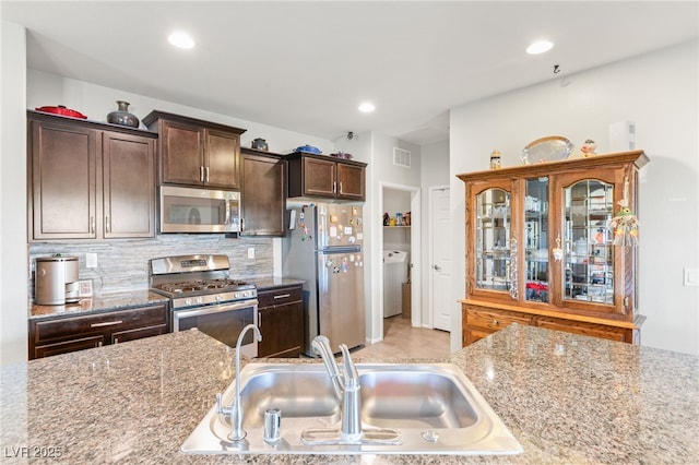 kitchen featuring backsplash, light stone countertops, sink, and stainless steel appliances