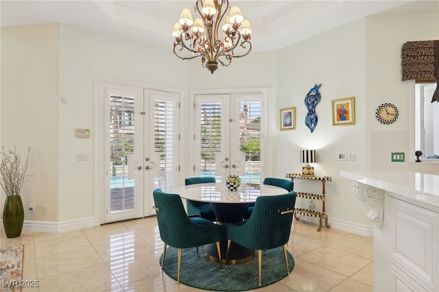 tiled dining space with an inviting chandelier, a tray ceiling, and french doors