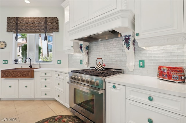 kitchen featuring custom exhaust hood, sink, high end stainless steel range, tasteful backsplash, and white cabinetry