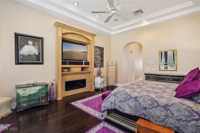 bedroom featuring ceiling fan, dark hardwood / wood-style flooring, a raised ceiling, and ornamental molding