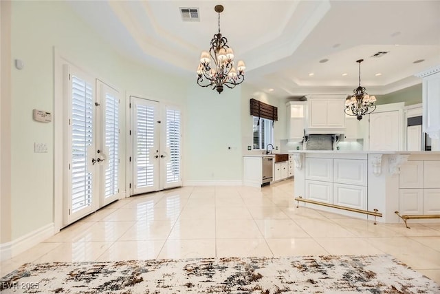 kitchen with a tray ceiling, french doors, pendant lighting, and a notable chandelier