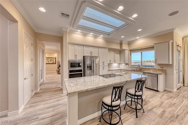 kitchen with light stone countertops, a skylight, a breakfast bar, stainless steel appliances, and a center island