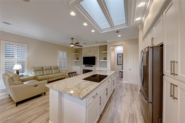 kitchen featuring built in features, white cabinetry, stainless steel refrigerator, and light stone counters