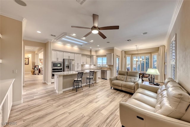 living room featuring crown molding, light hardwood / wood-style flooring, and ceiling fan with notable chandelier