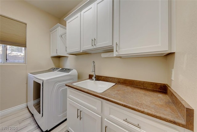 clothes washing area featuring washing machine and clothes dryer, sink, and cabinets