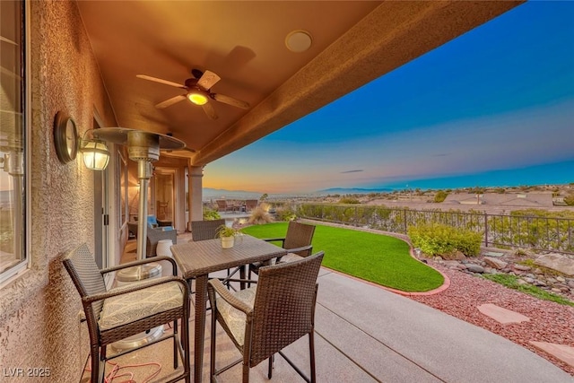 patio terrace at dusk with a yard and ceiling fan