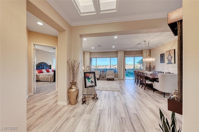 corridor featuring light hardwood / wood-style floors, crown molding, and a chandelier