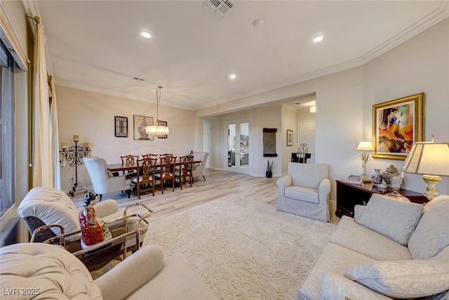 living room featuring light hardwood / wood-style floors, ornamental molding, and french doors