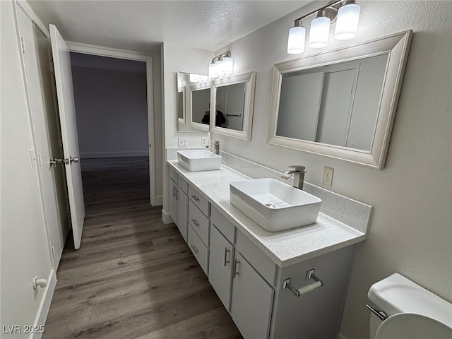 bathroom with toilet, vanity, a textured ceiling, and hardwood / wood-style flooring