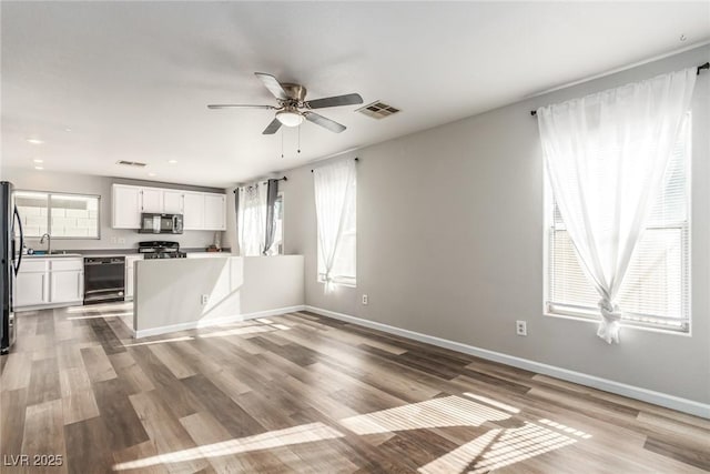 kitchen featuring white cabinetry, dishwasher, sink, light hardwood / wood-style flooring, and stainless steel fridge