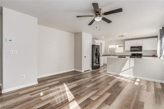 kitchen with black appliances, white cabinets, sink, and hardwood / wood-style floors