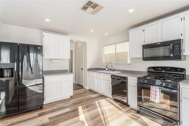 kitchen with sink, light hardwood / wood-style flooring, white cabinetry, and black appliances