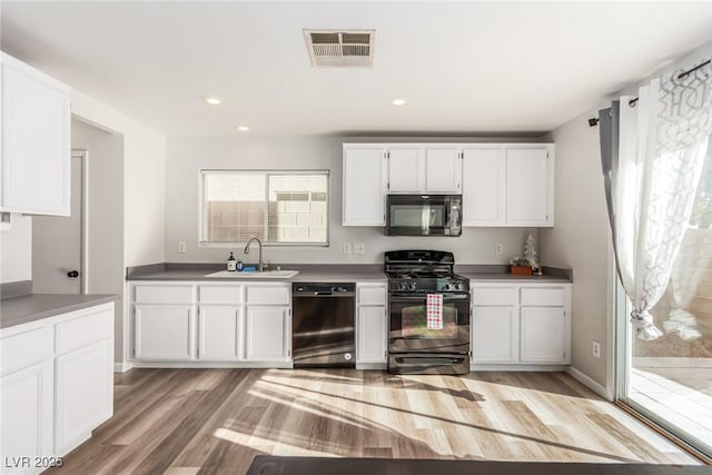 kitchen with black appliances, light hardwood / wood-style floors, white cabinetry, and sink