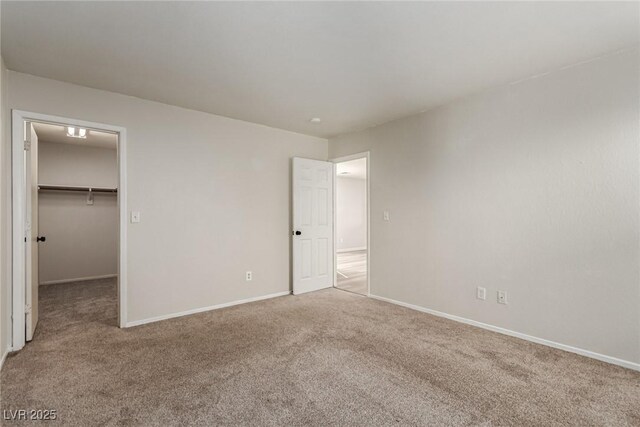 unfurnished bedroom featuring a walk in closet, a closet, and carpet floors