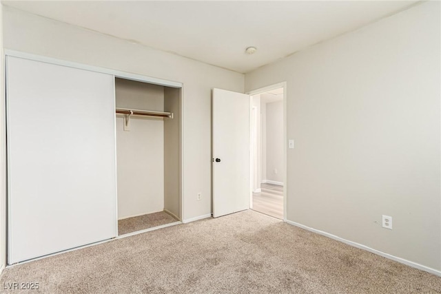 unfurnished bedroom with light carpet and a closet