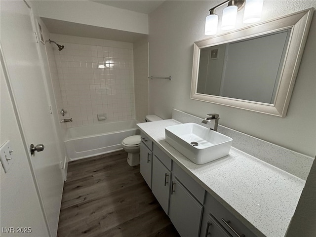 full bathroom featuring tiled shower / bath, vanity, wood-type flooring, and toilet