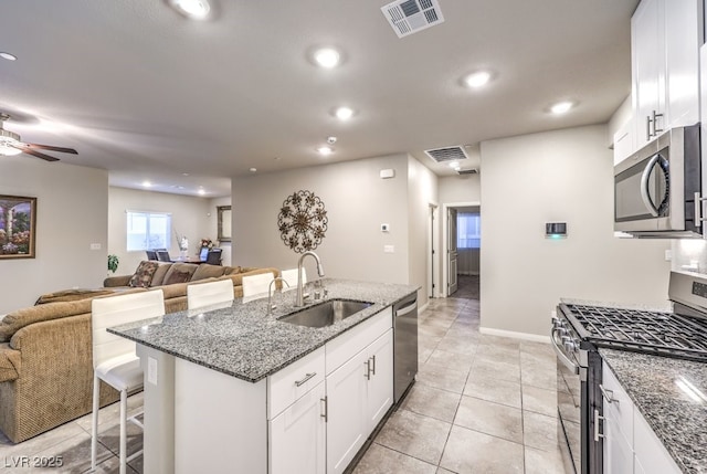 kitchen featuring sink, a breakfast bar, appliances with stainless steel finishes, white cabinetry, and a kitchen island with sink