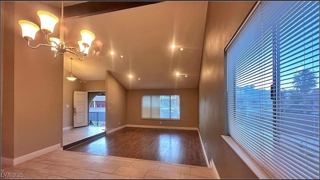 spare room with wood-type flooring, vaulted ceiling, and an inviting chandelier