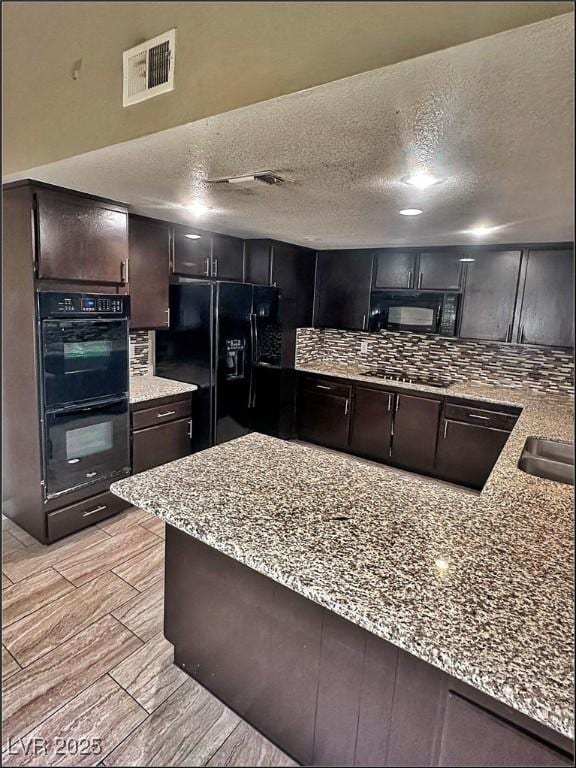 kitchen with light stone countertops, dark brown cabinets, a textured ceiling, sink, and black appliances