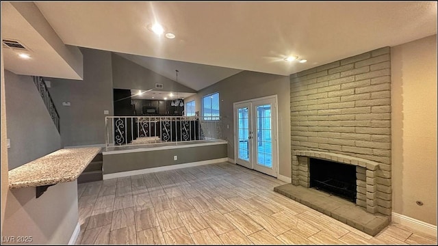 living room featuring light hardwood / wood-style flooring, lofted ceiling, a fireplace, and french doors