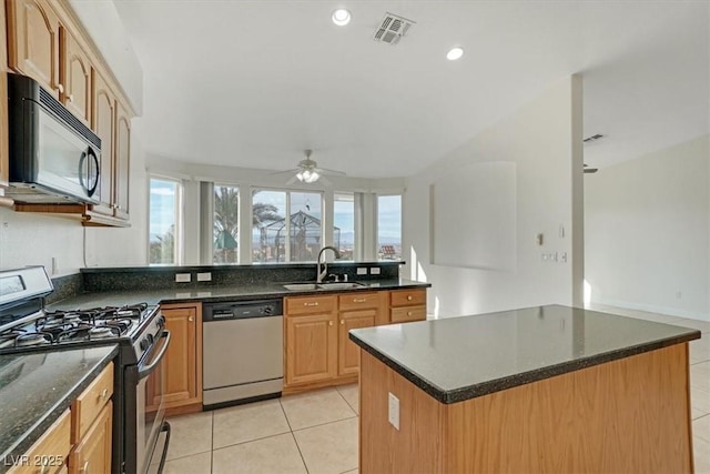 kitchen with ceiling fan, sink, light tile patterned floors, a kitchen island, and appliances with stainless steel finishes