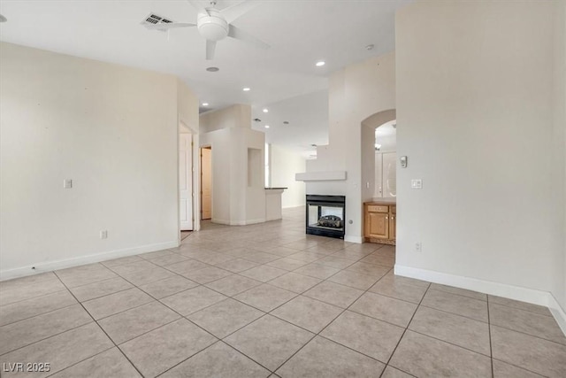 unfurnished living room with ceiling fan, a multi sided fireplace, and light tile patterned floors