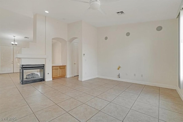 unfurnished living room with a multi sided fireplace, light tile patterned floors, and ceiling fan with notable chandelier