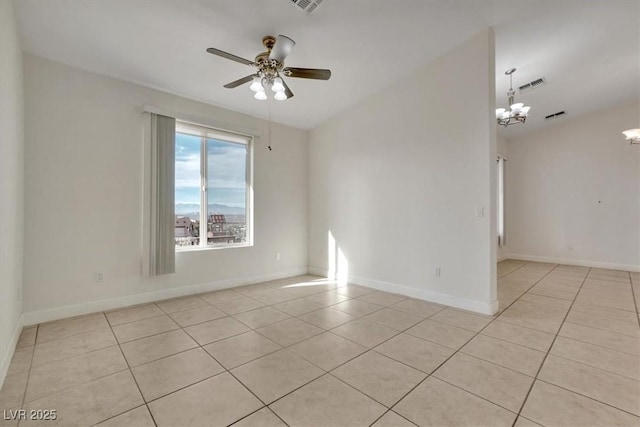 tiled spare room with ceiling fan with notable chandelier