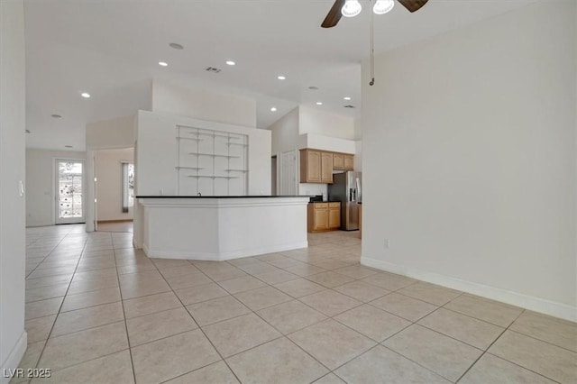 interior space featuring stainless steel fridge, a towering ceiling, light tile patterned floors, and ceiling fan