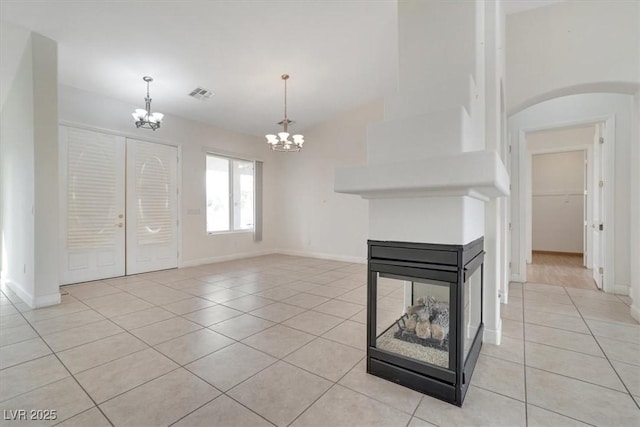 unfurnished living room featuring french doors, light tile patterned floors, and a notable chandelier