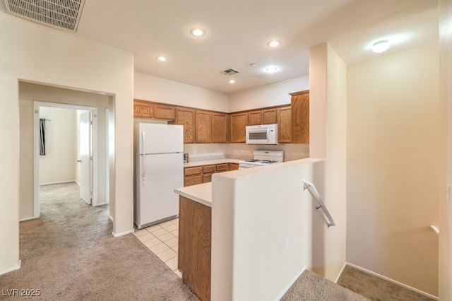 kitchen featuring kitchen peninsula, white appliances, and light carpet