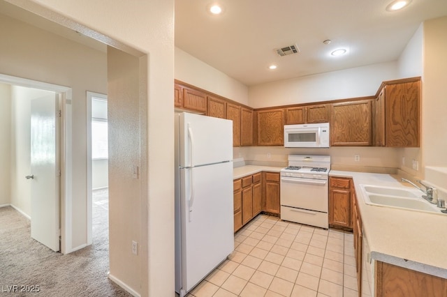 kitchen featuring white appliances, sink, and light carpet