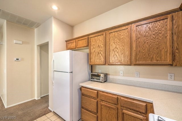 kitchen featuring white refrigerator, light colored carpet, and range