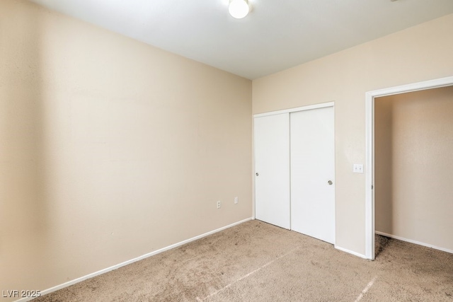 unfurnished bedroom with light colored carpet and a closet