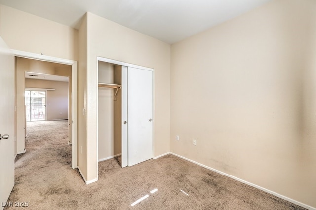 unfurnished bedroom with light carpet and a closet