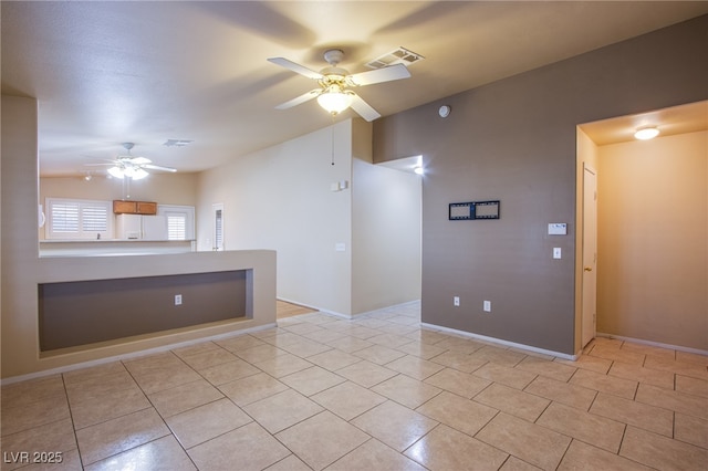 empty room featuring lofted ceiling, light tile patterned floors, and ceiling fan