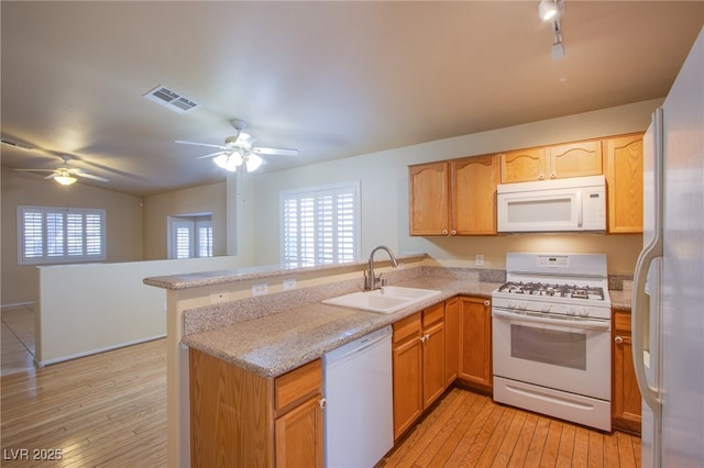 kitchen with sink, white appliances, light stone counters, light hardwood / wood-style floors, and kitchen peninsula