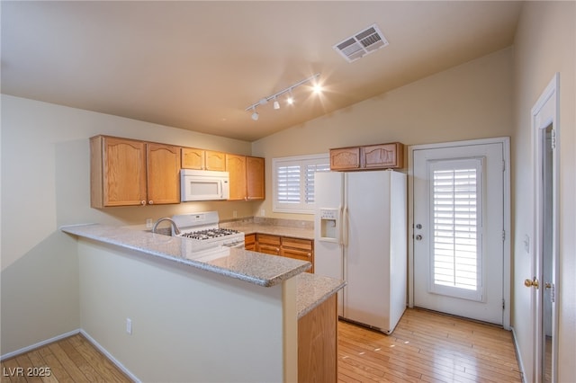 kitchen with light stone counters, vaulted ceiling, light hardwood / wood-style flooring, kitchen peninsula, and white appliances