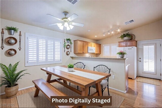 dining room with lofted ceiling, ceiling fan, and light wood-type flooring