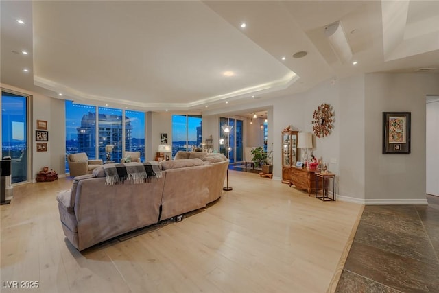 living room featuring light wood-type flooring and a raised ceiling