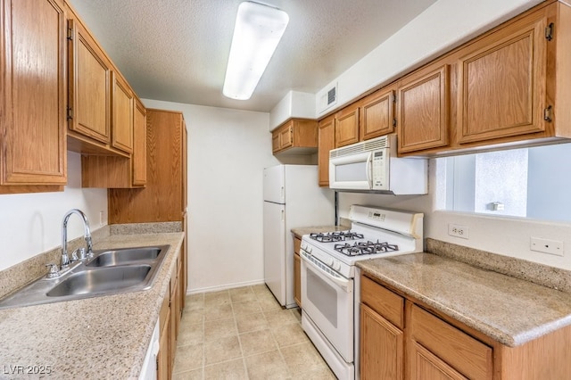 kitchen featuring a textured ceiling, white appliances, and sink