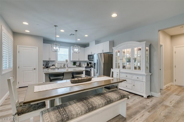 kitchen featuring tasteful backsplash, white cabinets, stainless steel appliances, and decorative light fixtures