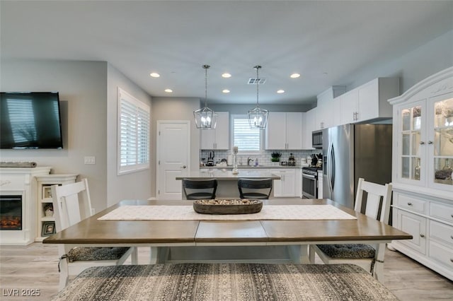 kitchen featuring pendant lighting, decorative backsplash, a kitchen island, white cabinetry, and stainless steel appliances