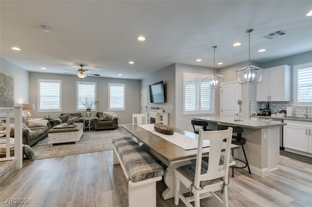 dining room featuring ceiling fan with notable chandelier, light hardwood / wood-style floors, and plenty of natural light