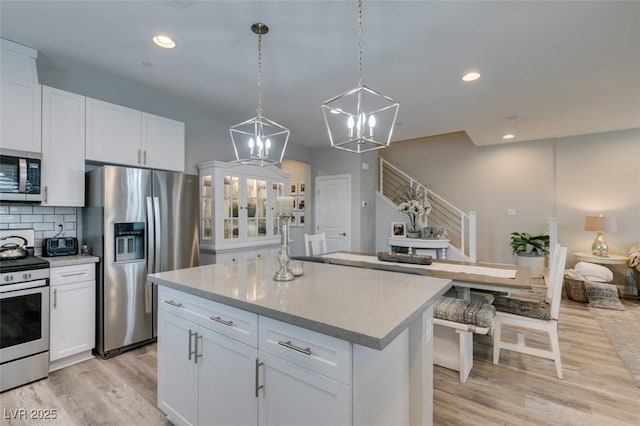 kitchen with decorative backsplash, white cabinetry, a kitchen island, and stainless steel appliances