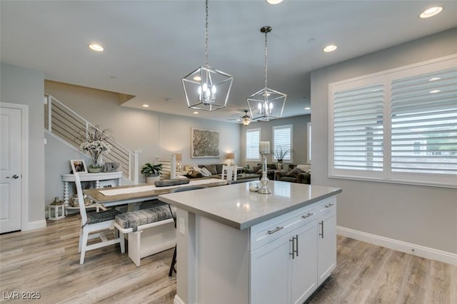 kitchen with ceiling fan, white cabinets, a center island, light hardwood / wood-style floors, and hanging light fixtures